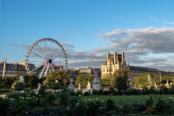 La Grande Roue de Paris et le pavillon de Marsan du Musée du Louvre bordant le Jardin des Tuileries sous un ciel de fin de jo