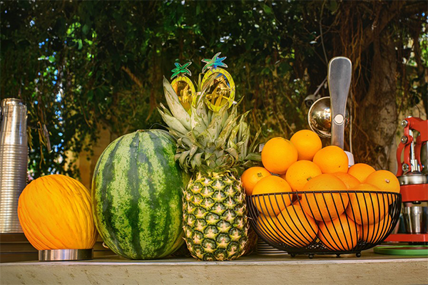 Sélection de fruits tropicaux frais sur un étal en Guadeloupe, incluant une pastèque, un ananas mûr et un panier d'orang