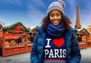 Femme devant la tour Eiffel et un marché de Noël à Paris.