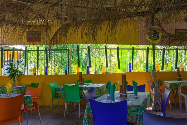Cadre coloré et ambiance typique de la Guadeloupe. Terrasse sous carbet du restaurant Chez Olivier à Sainte Rose, proposant u