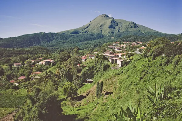 Panorama de la Montagne Pelée surplombant les reliefs verdoyants et les habitations de Saint-Pierre en Martinique, illustrant