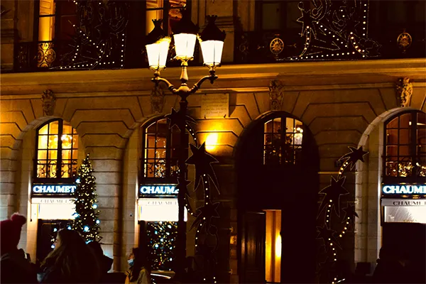 Façade illuminée de la joaillerie Chaumet sur la place Vendôme à Paris de nuit, ornée de décorations de Noël scintillantes.