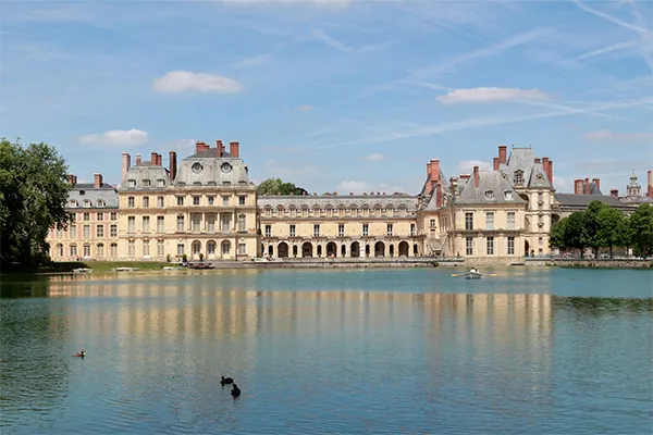 Vue sur la façade classique du Château de Fontainebleau se reflétant dans les eaux calmes de l étang aux Carpes, sous un ciel