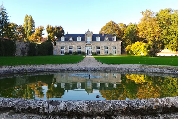 Façade d une demeure bourgeoise en pierre de taille avec un jardin verdoyant et un grand bassin circulaire au premier plan, r