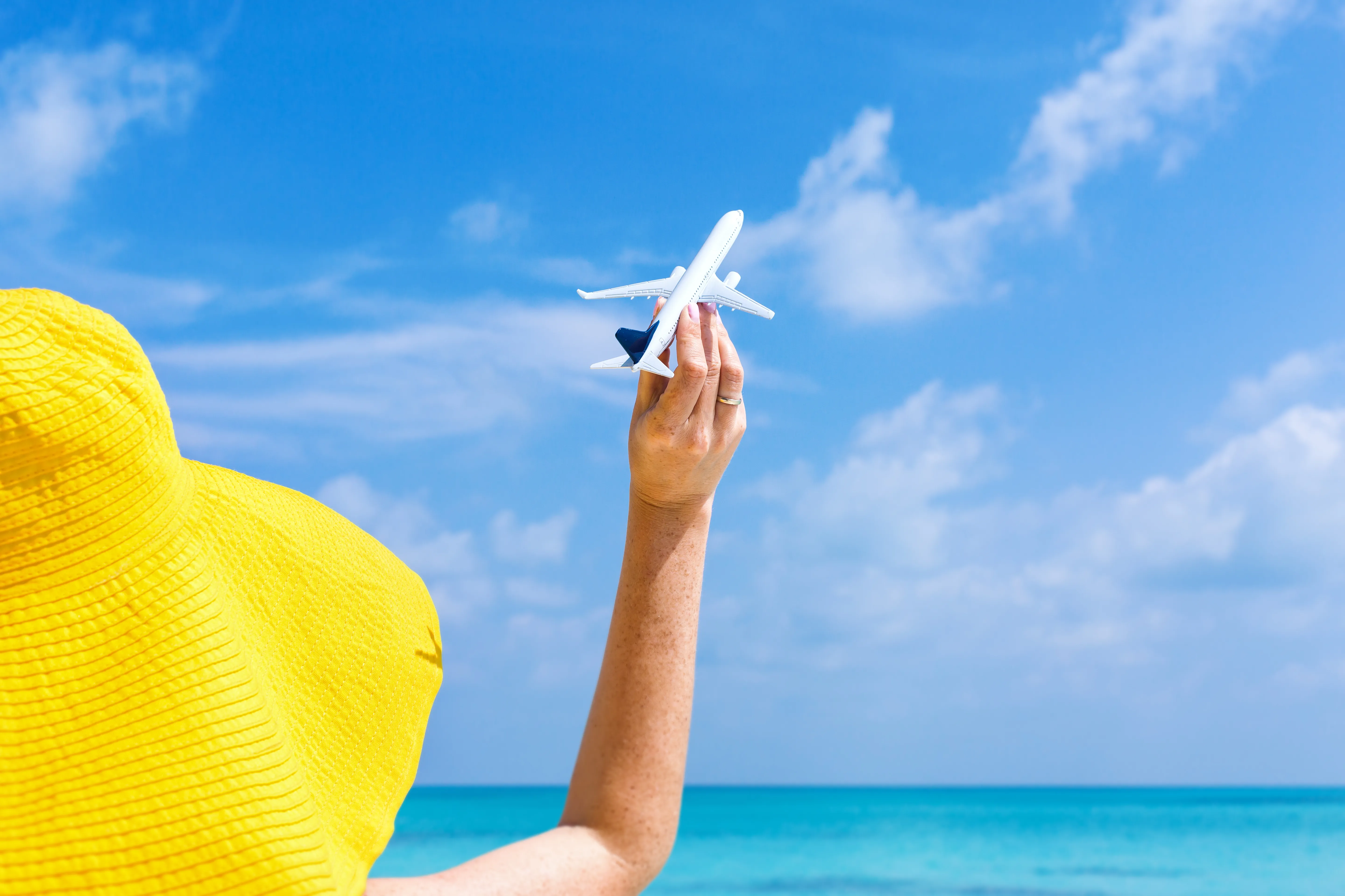 Femme tenant un petit avion sur une plage