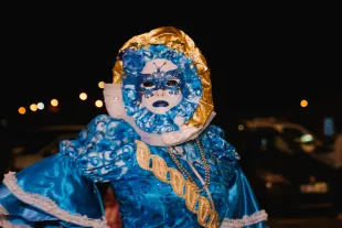 personne déguisée en Touloulou, personnage emblématique du carnaval de Guyane, vêtue d'un costume de carnaval bleu et or