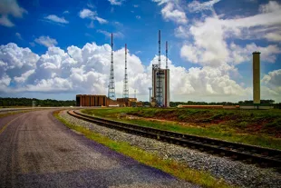 Vue panoramique des installations de lancement au Centre Spatial Guyanais à Kourou, incluant le pas de tir d'Ariane 6 et les pylônes de protection contre la foudre sous un ciel tropical.