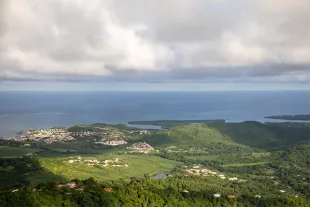 Vue panoramique depuis la montagne du Vauclin en Martinique offrant un spectacle grandiose sur le littoral atlantique, les plaines agricoles verdoyantes et les récifs coralliens au large.