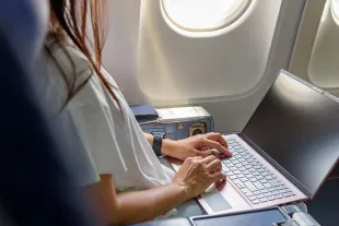 Femme travaillant sur son ordinateur à bord d'un avion près d'un hublot