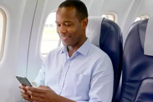 Homme assis sur un siège à bord d'un avion fixant son téléphone